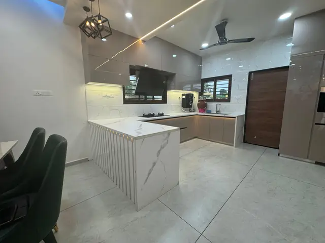 Modern island kitchen with white quartz countertop and false ceiling lighting