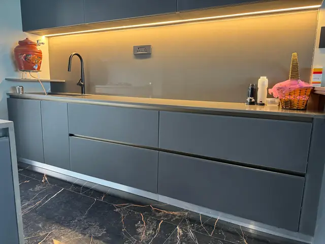 Dark handleless base units with warm under-cabinet lighting