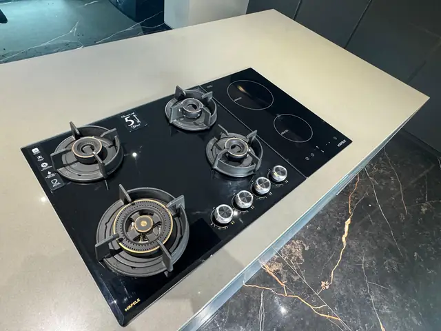 Five-burner black hob installed on a white island countertop