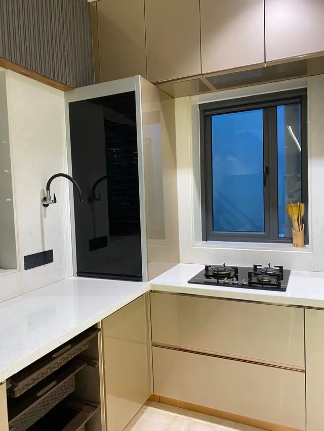 Compact beige L-shape kitchen with built-in hob and window